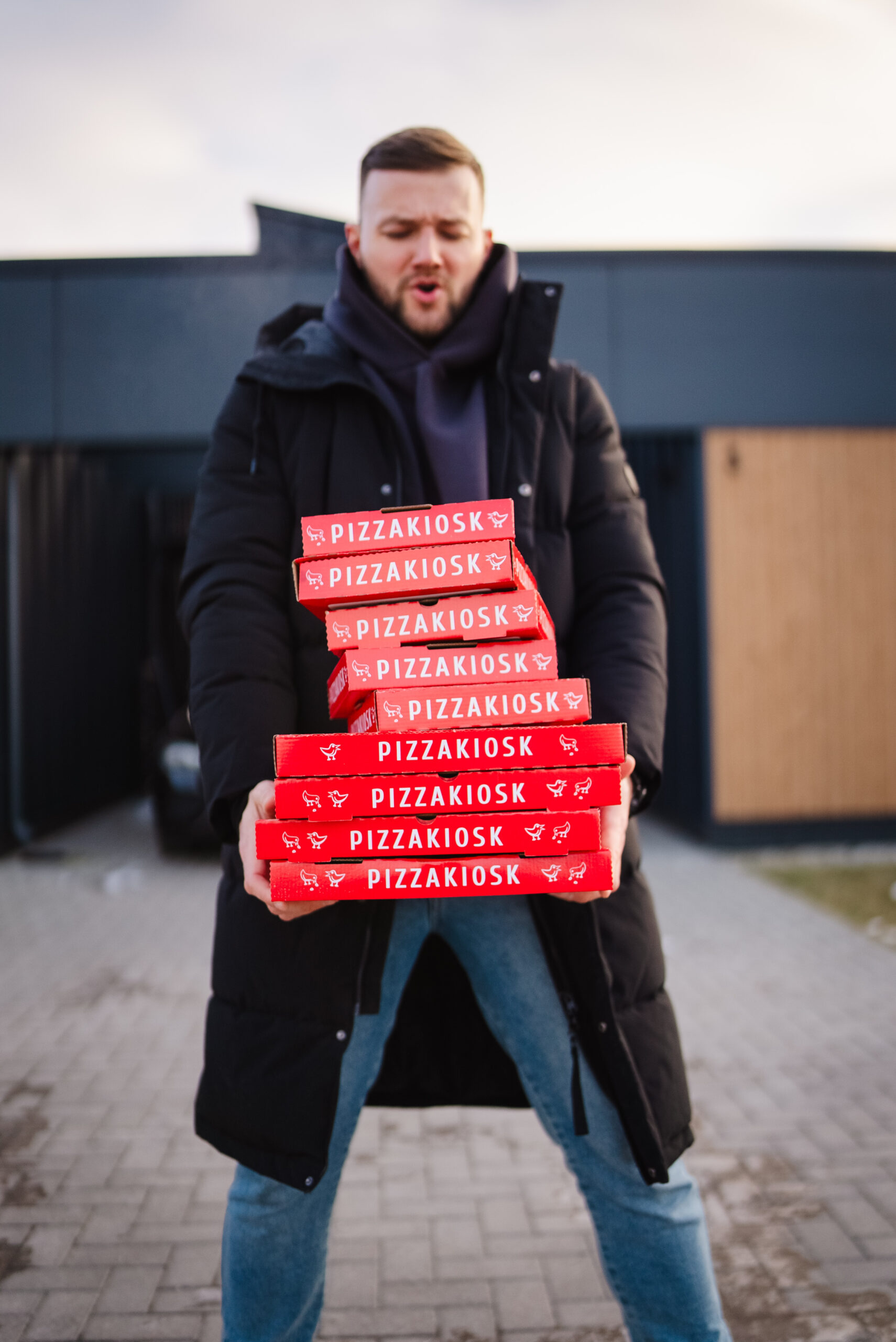 Mees hoiab käes suure hulga Pizzakioski karpe